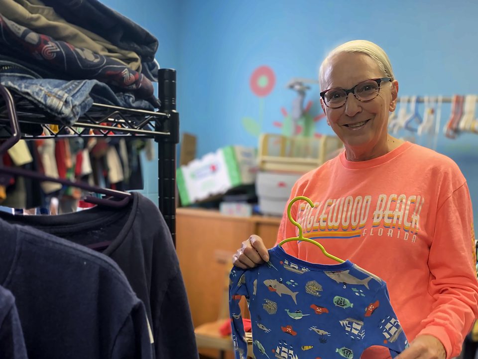 Volunteer holding up a pair of children's pajamas at Kid's Kloset