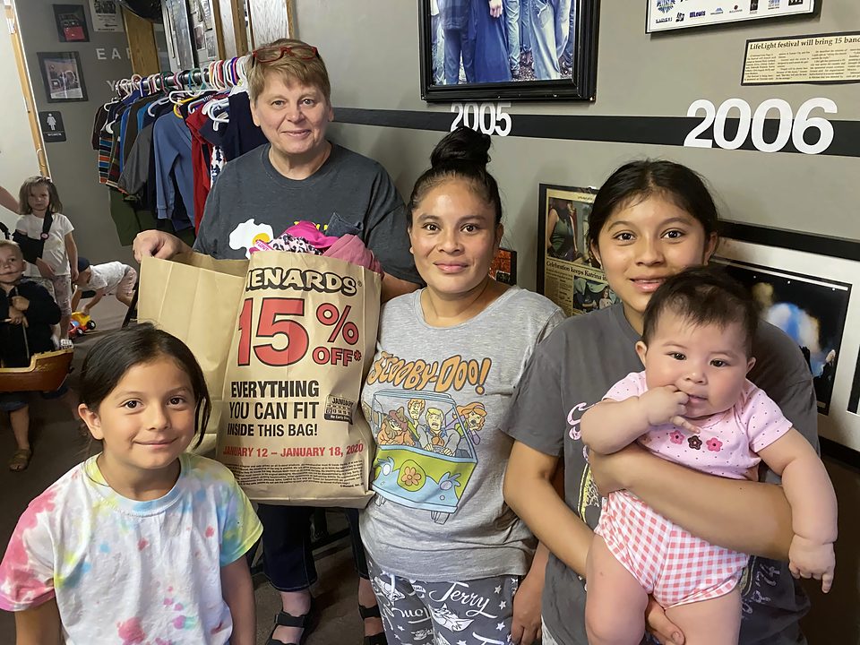 A mom and her children holding a shopping bag of clothes at Kid's Kloset